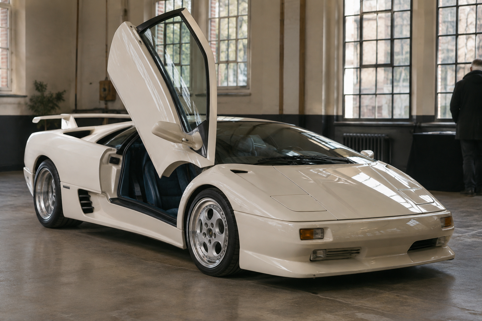 White 1994 Lamborghini Diablo SE30 at a London auction preview, with its scissor door raised and blue Alcantara cabin visible.